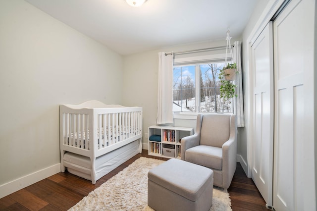 bedroom with a crib and dark hardwood / wood-style flooring