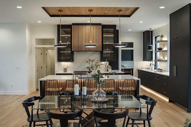 4163 Christopherson Ln SW, Rochester, MN 55902 - kitchen featuring dark cabinetry, open shelves, light wood-type flooring, decorative backsplash, and an island with sink