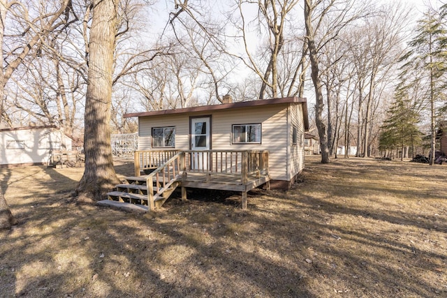 back of house with a wooden deck and a lawn