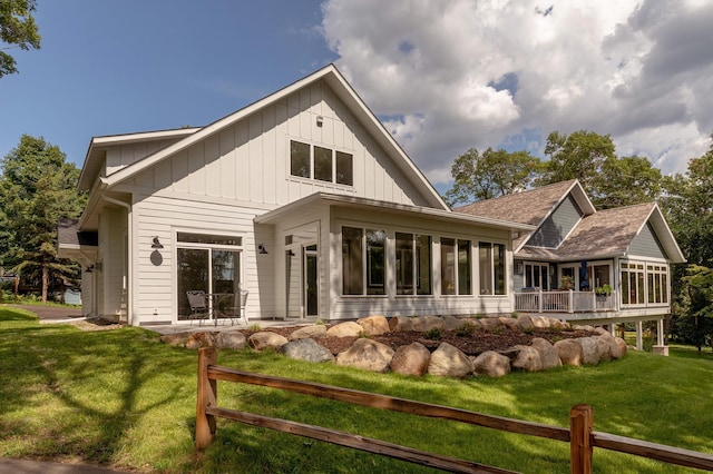 rear view of property with a lawn and a sunroom