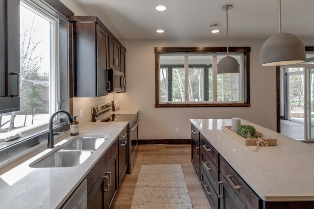 kitchen featuring hanging light fixtures, stainless steel appliances, backsplash, and a healthy amount of sunlight