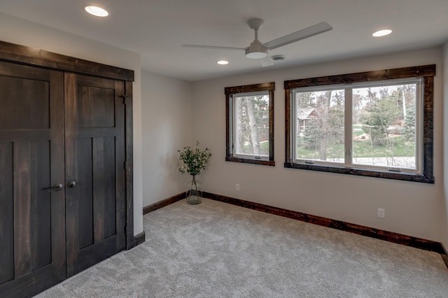 unfurnished bedroom featuring light colored carpet, ceiling fan, and multiple windows