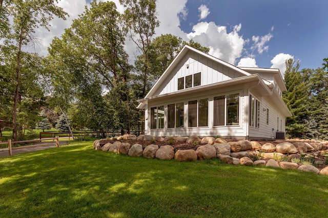 rear view of house featuring central AC and a lawn