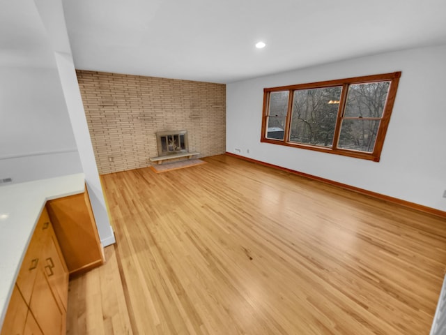 unfurnished living room featuring light wood-type flooring and a brick fireplace