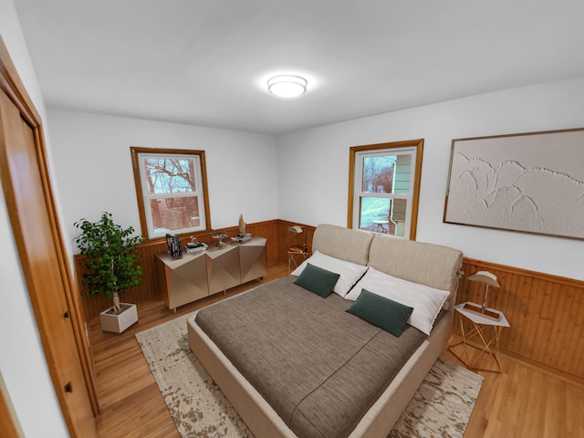 bedroom featuring multiple windows, wooden walls, and light hardwood / wood-style flooring