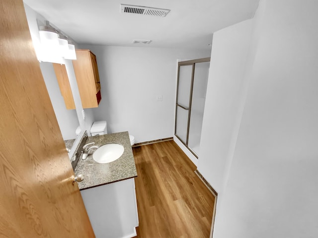 bathroom featuring hardwood / wood-style flooring, vanity, toilet, and a shower with shower door