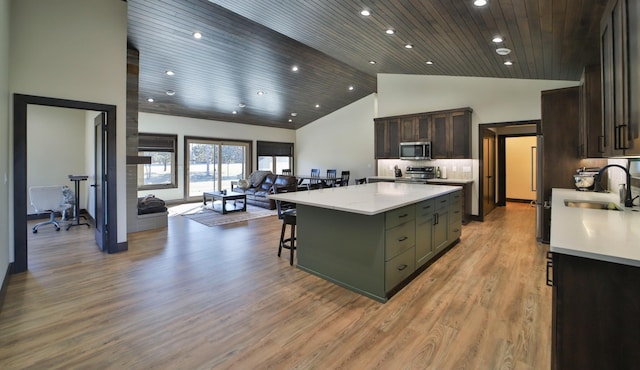 kitchen featuring a center island, high vaulted ceiling, sink, light wood-type flooring, and a kitchen breakfast bar