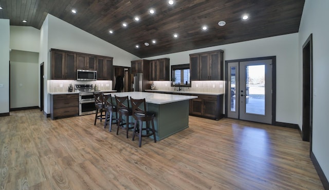 kitchen featuring high vaulted ceiling, light hardwood / wood-style floors, backsplash, and a kitchen island