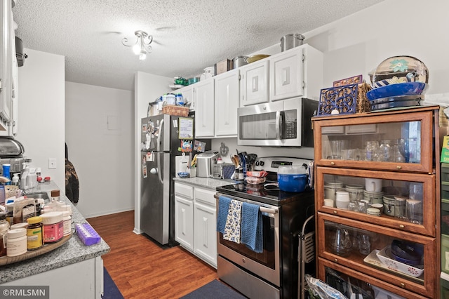 kitchen featuring dark wood-type flooring, sink, stainless steel appliances, white cabinets, and a textured ceiling