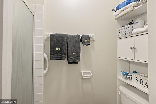 room details featuring toilet and a shower with shower door