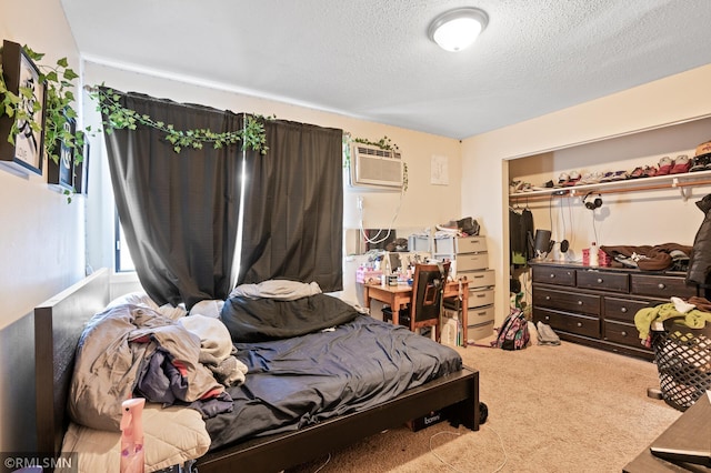 carpeted bedroom featuring a closet, a wall mounted air conditioner, and a textured ceiling