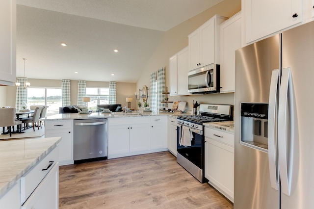 kitchen featuring an inviting chandelier, light stone counters, white cabinetry, stainless steel appliances, and light wood-type flooring