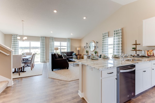 kitchen with light stone countertops, white cabinetry, stainless steel dishwasher, and light wood-type flooring