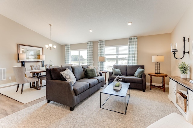 living room featuring an inviting chandelier, lofted ceiling, light carpet, and a textured ceiling