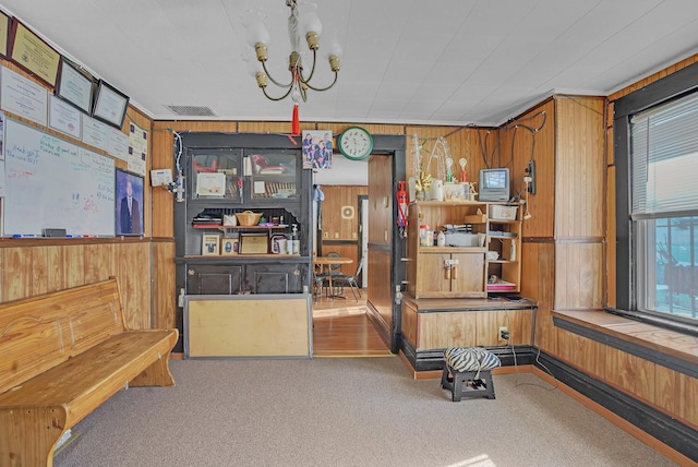 carpeted office featuring a notable chandelier and wood walls