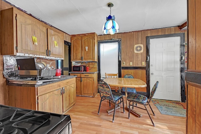 kitchen featuring stove, light hardwood / wood-style flooring, and hanging light fixtures