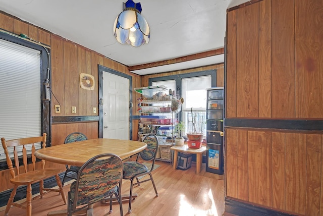 dining room with wood walls and light wood-type flooring