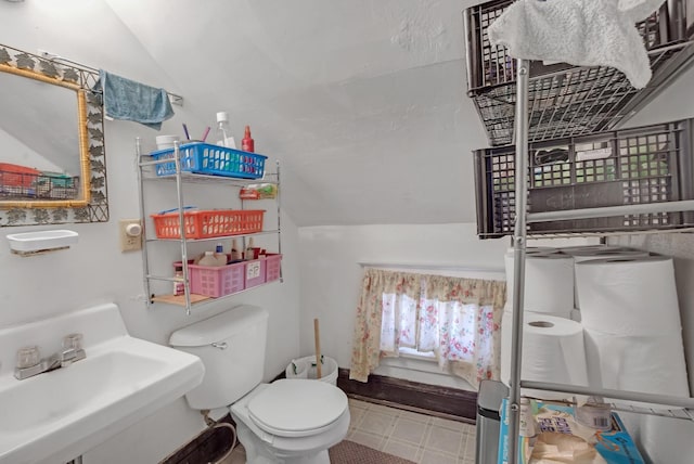 bathroom with toilet, tile floors, vaulted ceiling, and sink