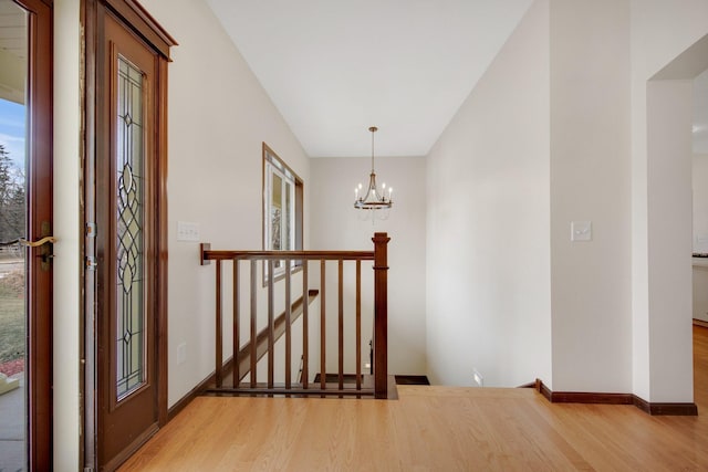 hallway with light wood-type flooring and a chandelier