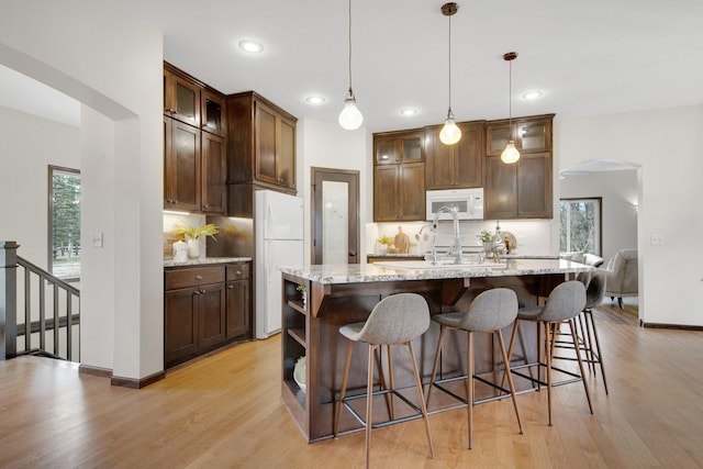 kitchen featuring decorative backsplash, pendant lighting, white appliances, and a kitchen island with sink