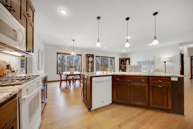 kitchen featuring backsplash, light hardwood / wood-style flooring, decorative light fixtures, and white appliances