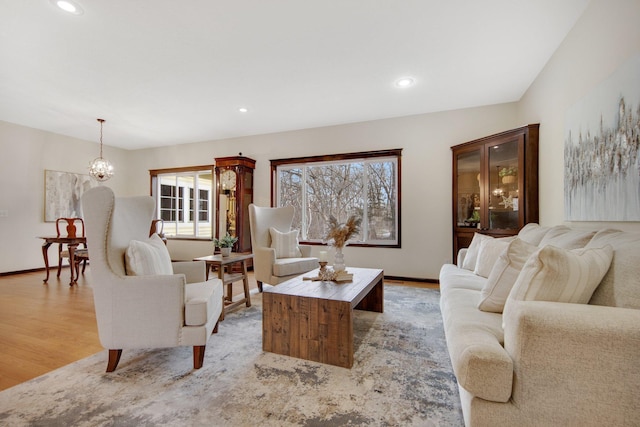 living room with light hardwood / wood-style flooring, a healthy amount of sunlight, and a notable chandelier