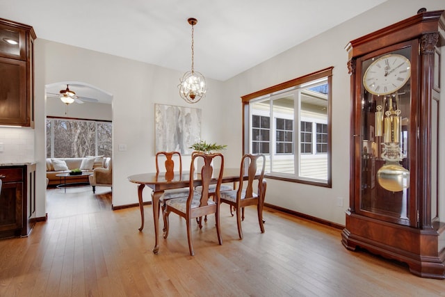 dining space featuring light wood-type flooring and ceiling fan with notable chandelier