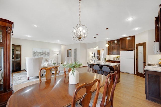 dining space featuring an inviting chandelier, light hardwood / wood-style flooring, and sink