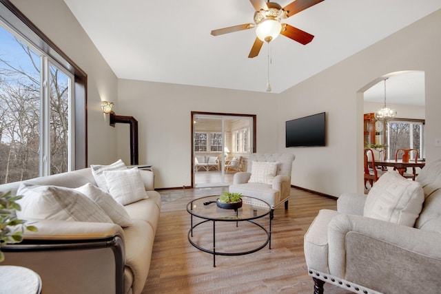 living room with light wood-type flooring and ceiling fan with notable chandelier