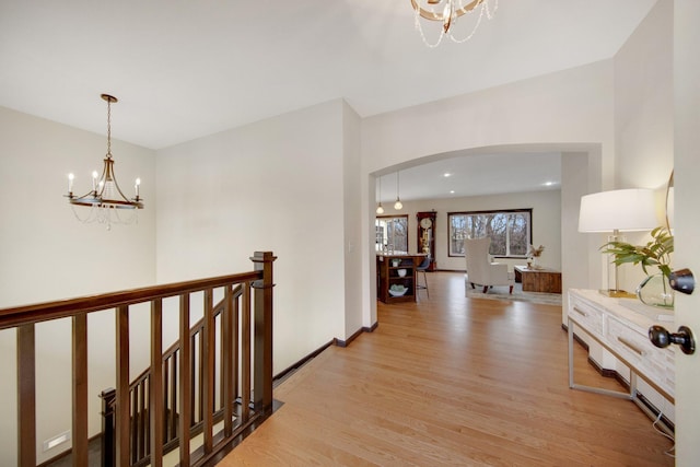 hallway featuring light wood-type flooring and an inviting chandelier