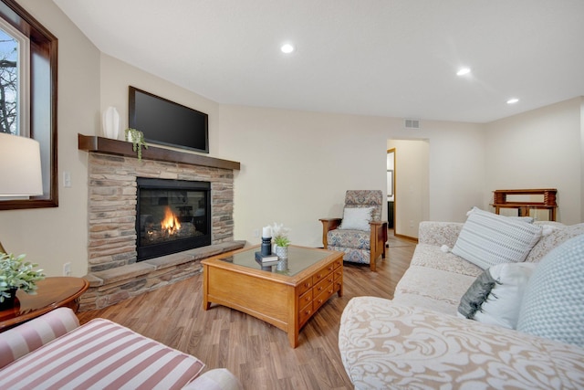 living room featuring a stone fireplace and light hardwood / wood-style floors