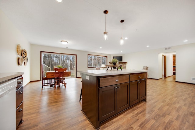 kitchen featuring dishwasher, light wood-type flooring, a kitchen island, and hanging light fixtures