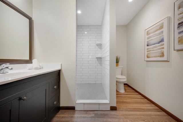 bathroom with tiled shower, wood-type flooring, vanity, and toilet