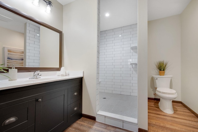 bathroom featuring tiled shower, wood-type flooring, vanity, and toilet