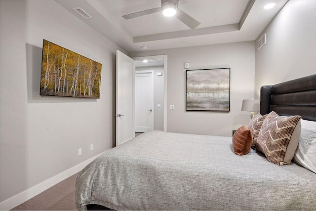 bedroom with ceiling fan, a tray ceiling, and carpet flooring