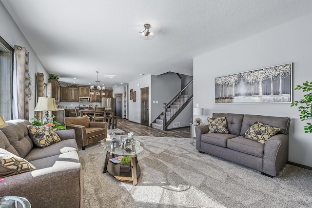 carpeted living room featuring an inviting chandelier and a textured ceiling