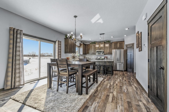 dining space featuring an inviting chandelier, hardwood / wood-style floors, and a textured ceiling