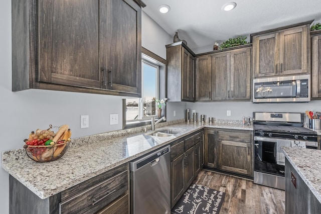 kitchen with sink, light stone counters, dark hardwood / wood-style flooring, stainless steel appliances, and dark brown cabinetry