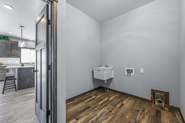 laundry area with a textured ceiling, washer hookup, and light hardwood / wood-style floors