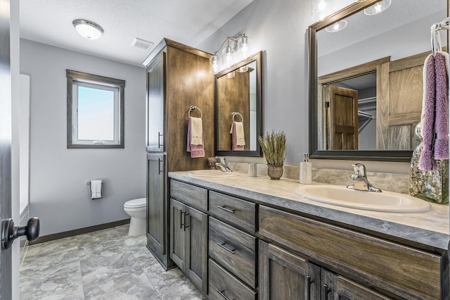 bathroom featuring a textured ceiling, tile floors, toilet, and dual bowl vanity