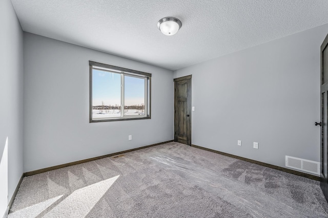 empty room featuring dark carpet and a textured ceiling