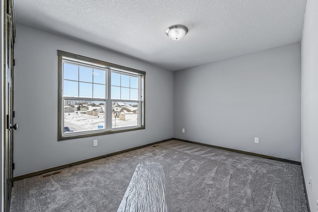 carpeted empty room with a textured ceiling