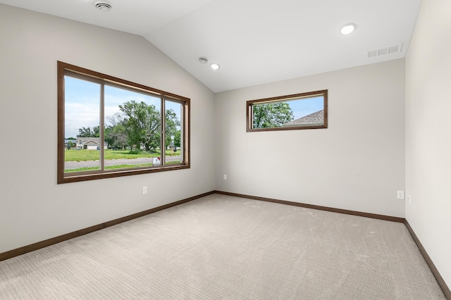 carpeted spare room with vaulted ceiling