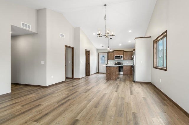 kitchen featuring stainless steel appliances, hanging light fixtures, hardwood / wood-style floors, and a notable chandelier