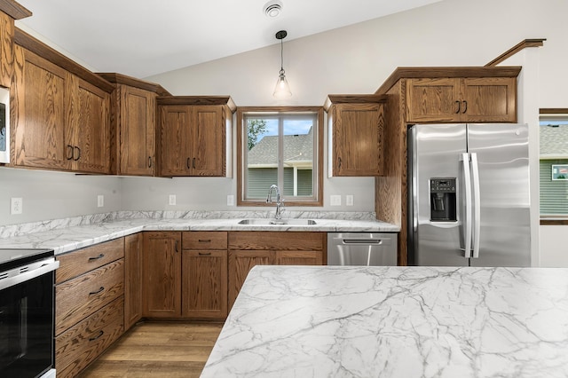 kitchen with pendant lighting, sink, lofted ceiling, light hardwood / wood-style flooring, and appliances with stainless steel finishes