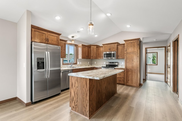 kitchen with light wood-type flooring, vaulted ceiling, a center island, appliances with stainless steel finishes, and decorative light fixtures