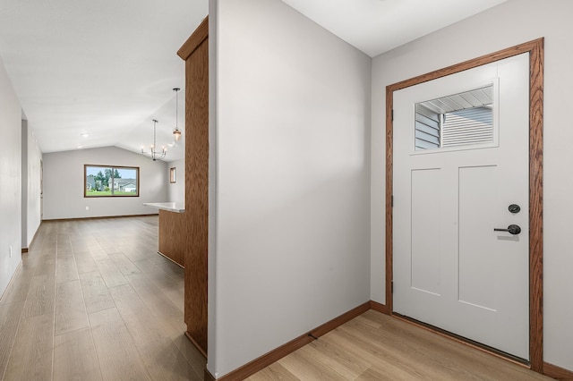 foyer entrance with lofted ceiling, light wood-type flooring, and an inviting chandelier