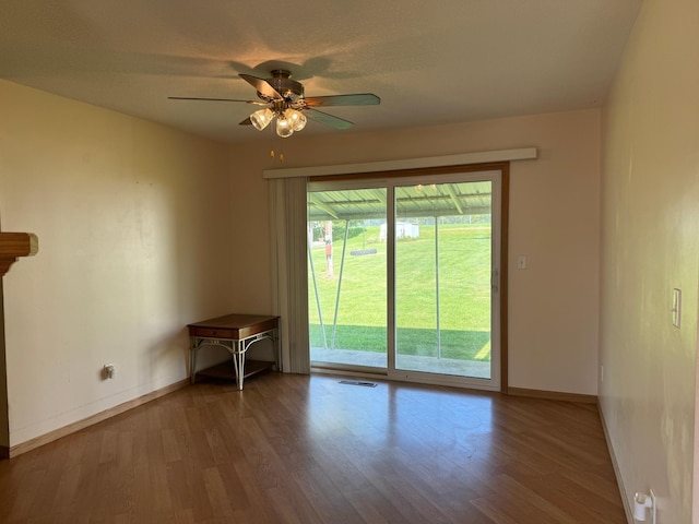 unfurnished room with a ceiling fan, wood finished floors, visible vents, and baseboards