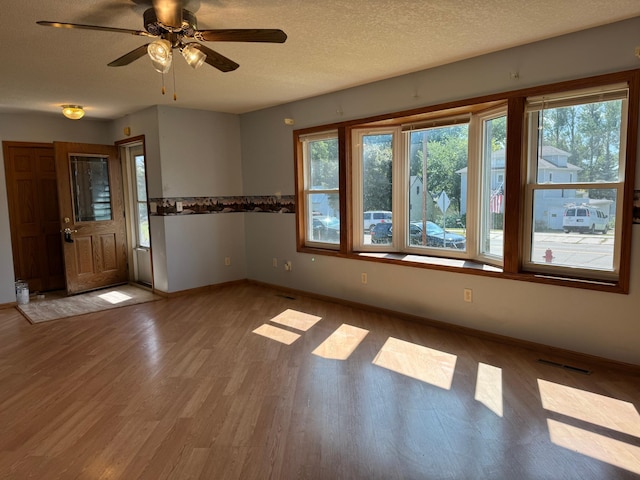 unfurnished room featuring visible vents, ceiling fan, baseboards, wood finished floors, and a textured ceiling