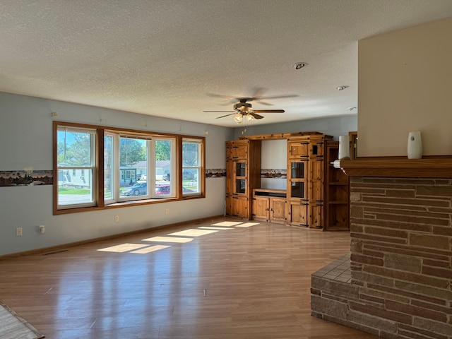 unfurnished living room featuring a textured ceiling, baseboards, and wood finished floors